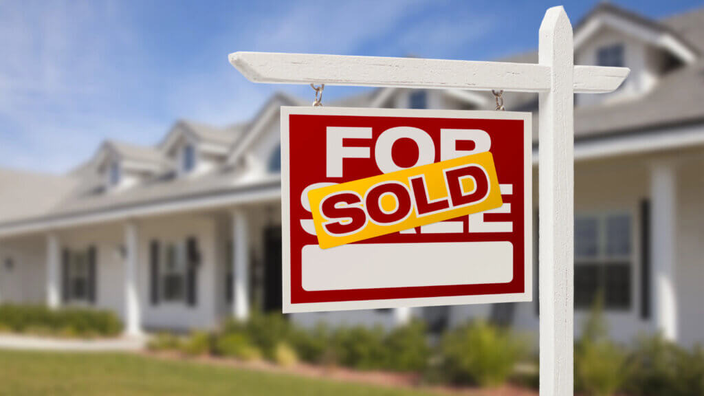 Modern house with red SOLD sign in front yard representing quick cash home sale success